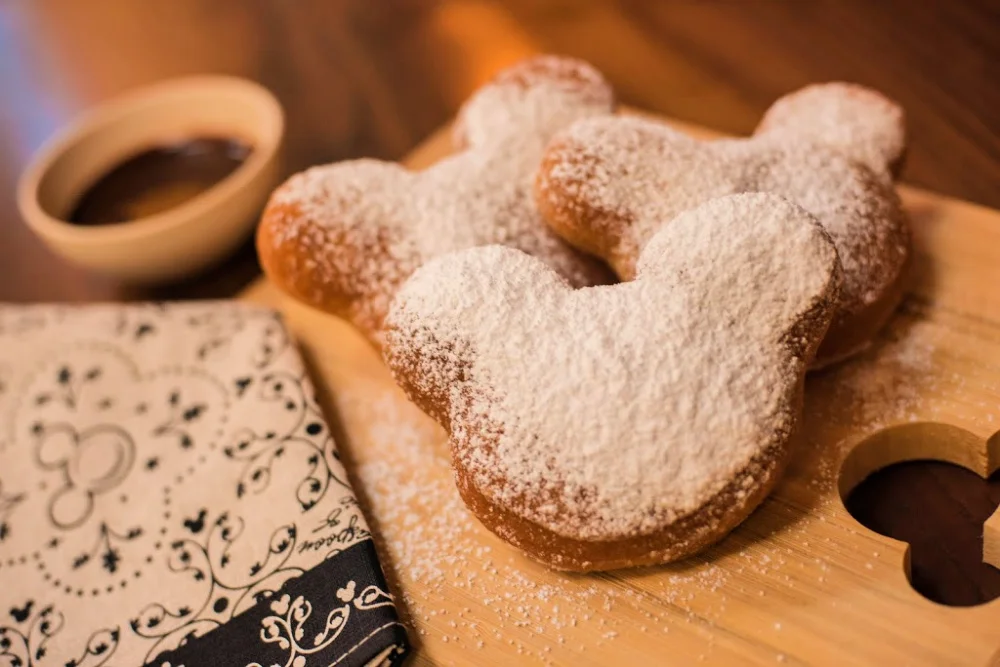 Buñuelos de Mickey Mouse cubiertos de azúcar glass sobre una tabla de madera