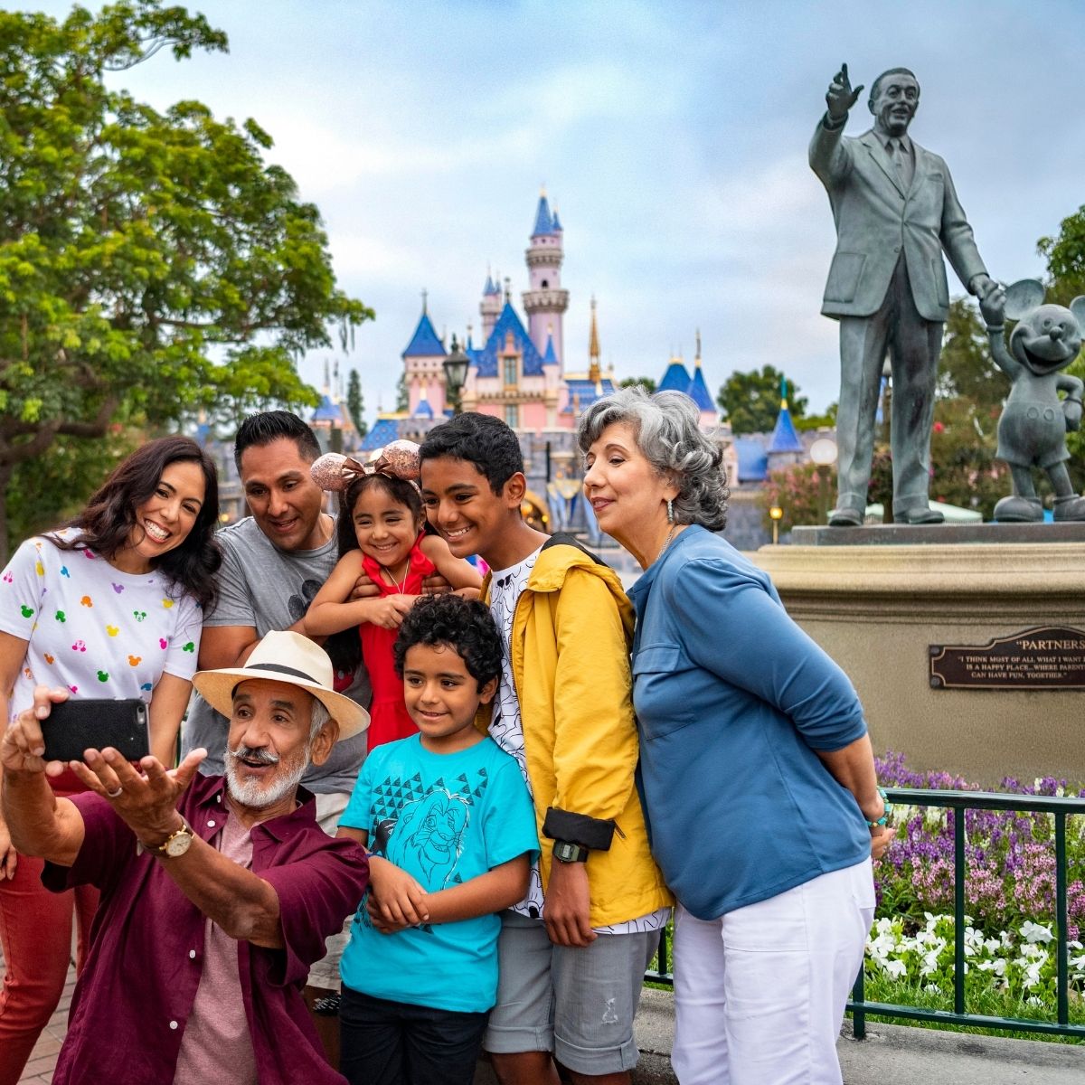 family taking a picture in front of the partner statue at Disneyland